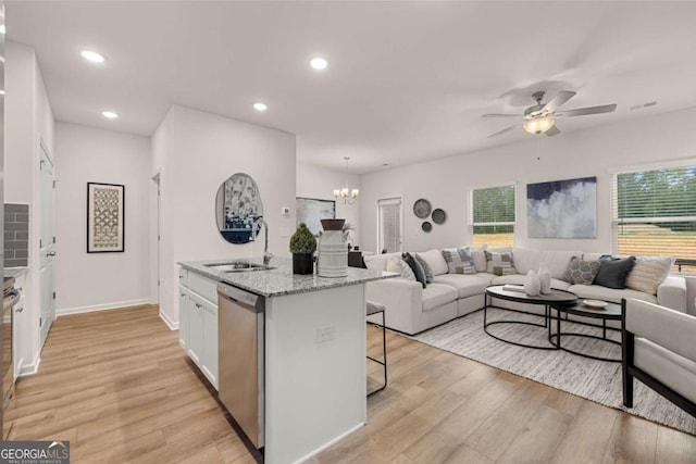 kitchen featuring open floor plan, a sink, light wood-style floors, and dishwasher