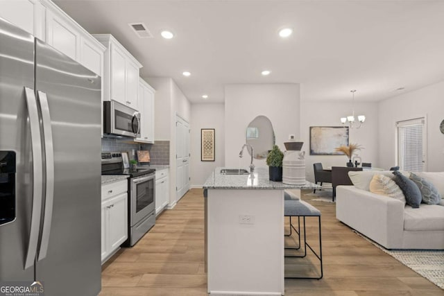 kitchen featuring light wood-type flooring, stainless steel appliances, a breakfast bar, a sink, and white cabinets