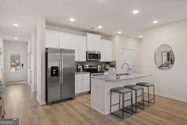 kitchen with light wood finished floors, a sink, white cabinets, and appliances with stainless steel finishes