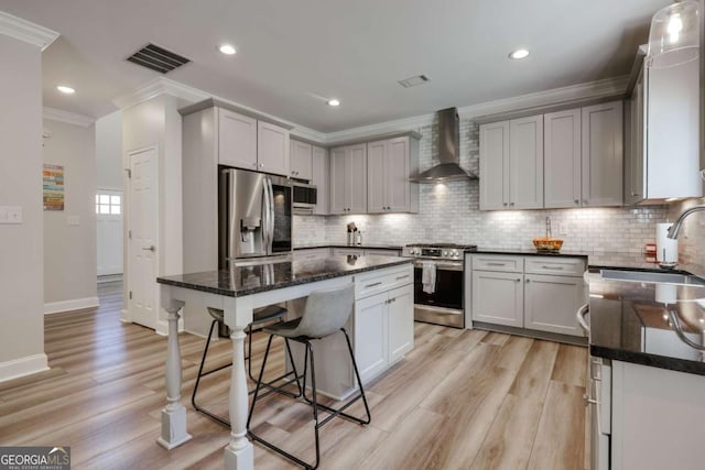 3065 Meadow Springs Dr, Watkinsville, GA 30677 - kitchen featuring appliances with stainless steel finishes, wall chimney range hood, crown molding, a breakfast bar, and light wood-type flooring