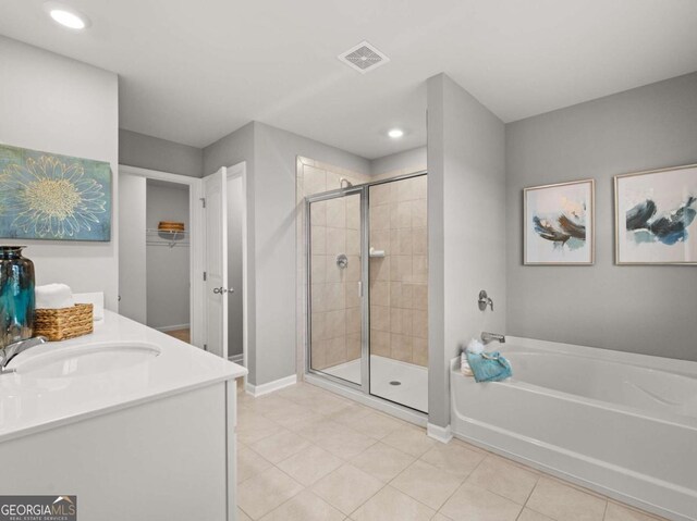 full bath with a stall shower, a spacious closet, tile patterned flooring, a bath, and visible vents