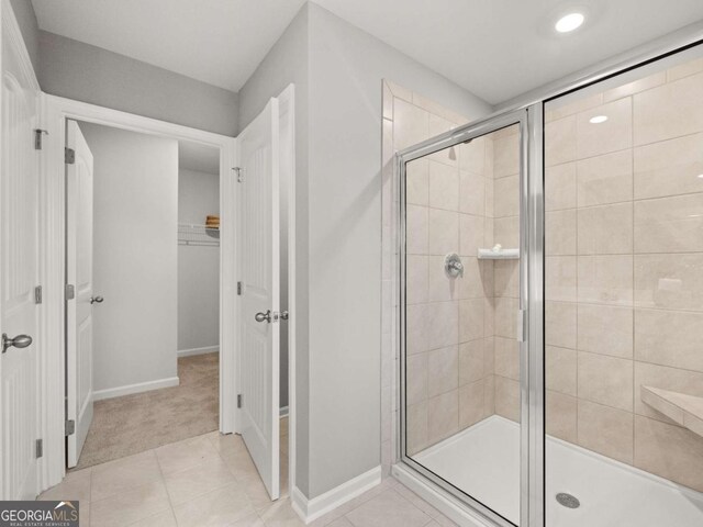 full bath with a spacious closet, tile patterned floors, baseboards, and a shower stall
