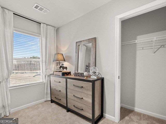 bedroom featuring baseboards, visible vents, a closet, and light colored carpet