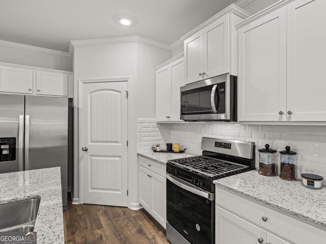 kitchen featuring crown molding, white cabinetry, tasteful backsplash, appliances with stainless steel finishes, and dark wood-type flooring