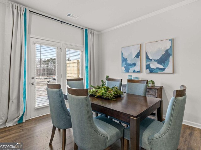 dining room featuring dark wood-style floors, visible vents, crown molding, and baseboards