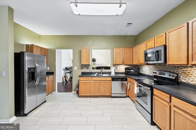 5330 Willow Park Blvd, South Fulton, GA 30349 - kitchen featuring stainless steel appliances, dark countertops, tasteful backsplash, a sink, and a textured ceiling