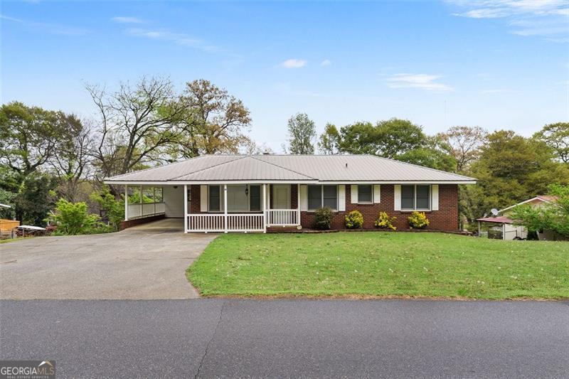 view of front of house featuring metal roof, driveway, a front lawn, a porch, and a carport