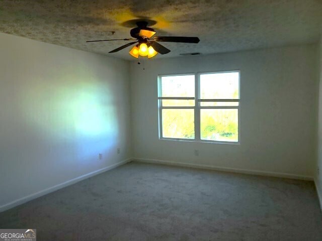 carpeted empty room featuring baseboards, ceiling fan, and visible vents