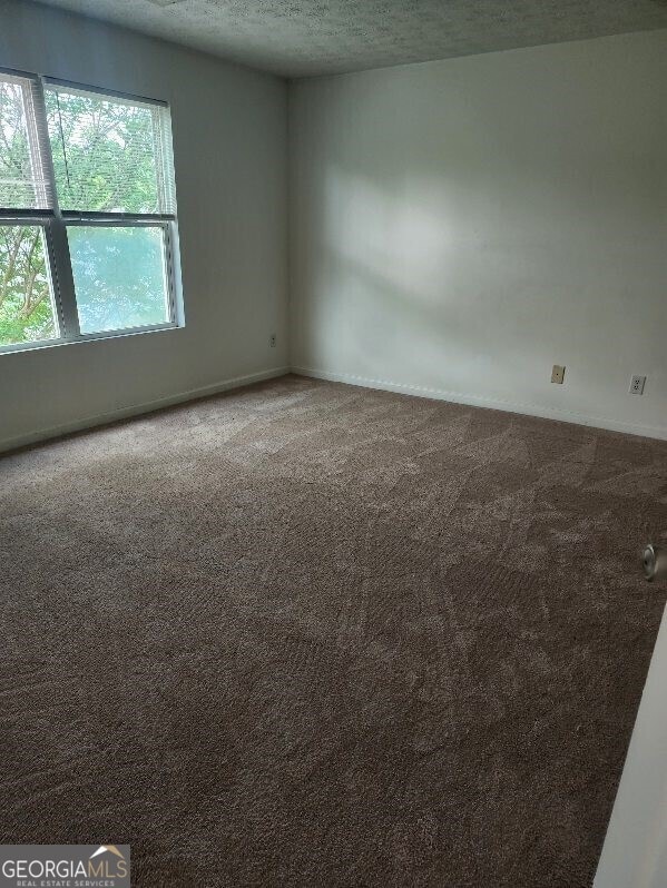 carpeted spare room featuring baseboards and a textured ceiling