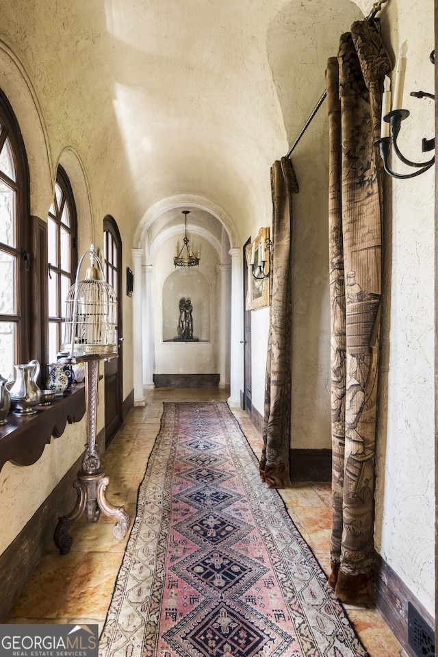 2100 W Wesley Rd, Atlanta, GA 30327 - corridor with a chandelier, arched walkways, stone tile floors, and a towering ceiling