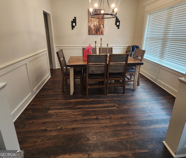 dining space featuring wainscoting, a decorative wall, dark wood-style flooring, and a chandelier