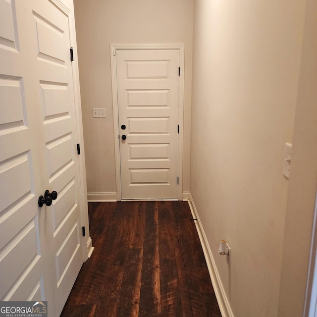 doorway featuring baseboards and dark wood-style floors