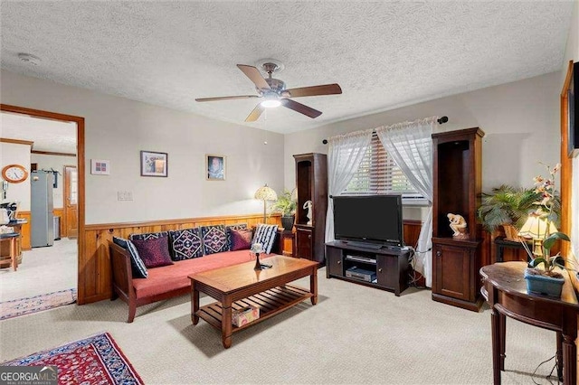 living area featuring ceiling fan, wainscoting, a textured ceiling, and light colored carpet