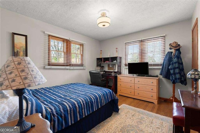 bedroom with a textured ceiling, multiple windows, and wood finished floors