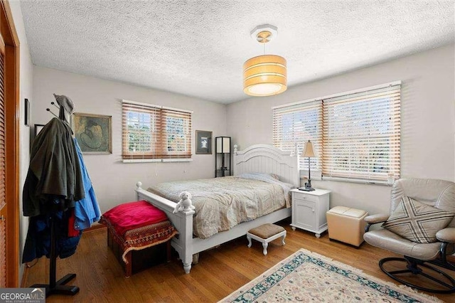 bedroom with a textured ceiling and wood finished floors