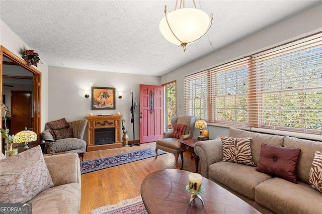 living room with a textured ceiling, wood finished floors, and a fireplace
