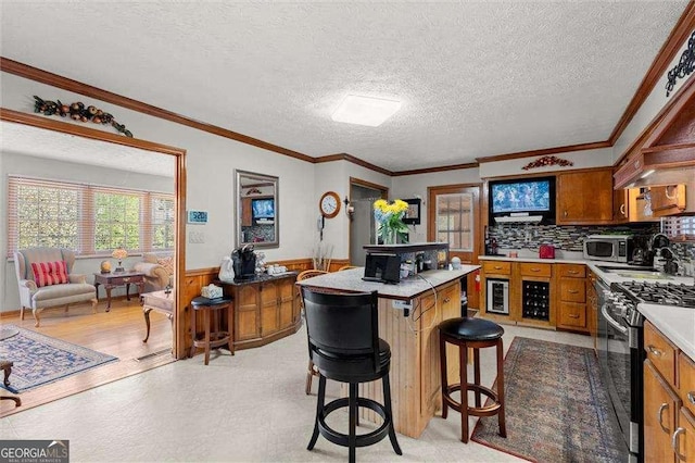 kitchen featuring wainscoting, light floors, a center island, brown cabinets, and gas stove