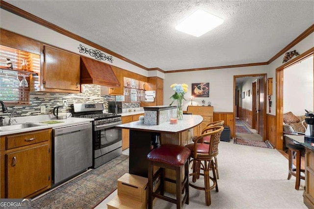 kitchen with crown molding, light countertops, a textured ceiling, a sink, and appliances with stainless steel finishes