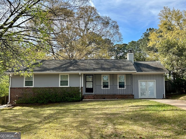 ranch-style home with a chimney, brick siding, a front lawn, board and batten siding, and covered porch