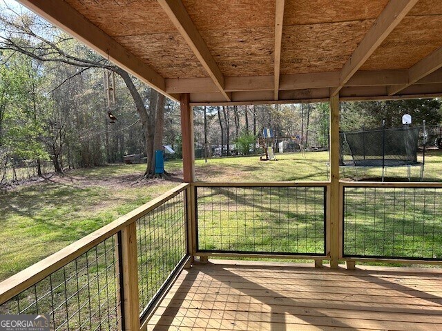 deck featuring a trampoline and a lawn