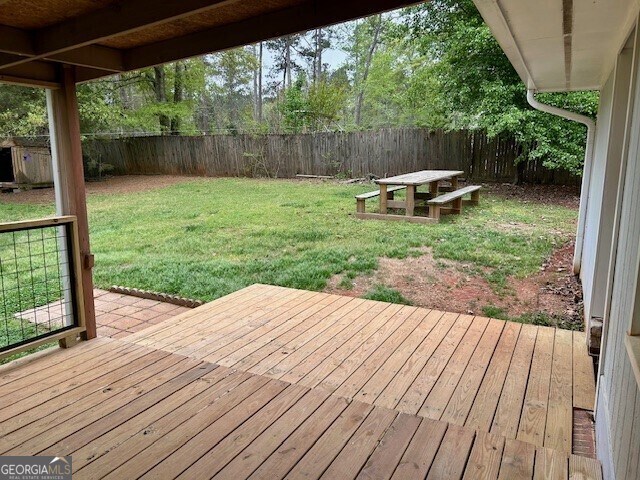 wooden terrace featuring a lawn and a fenced backyard