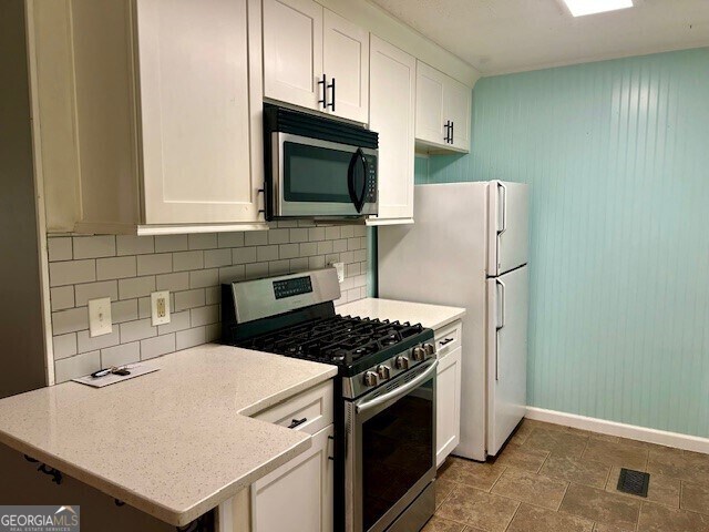 kitchen featuring tasteful backsplash, stainless steel appliances, baseboards, visible vents, and white cabinets