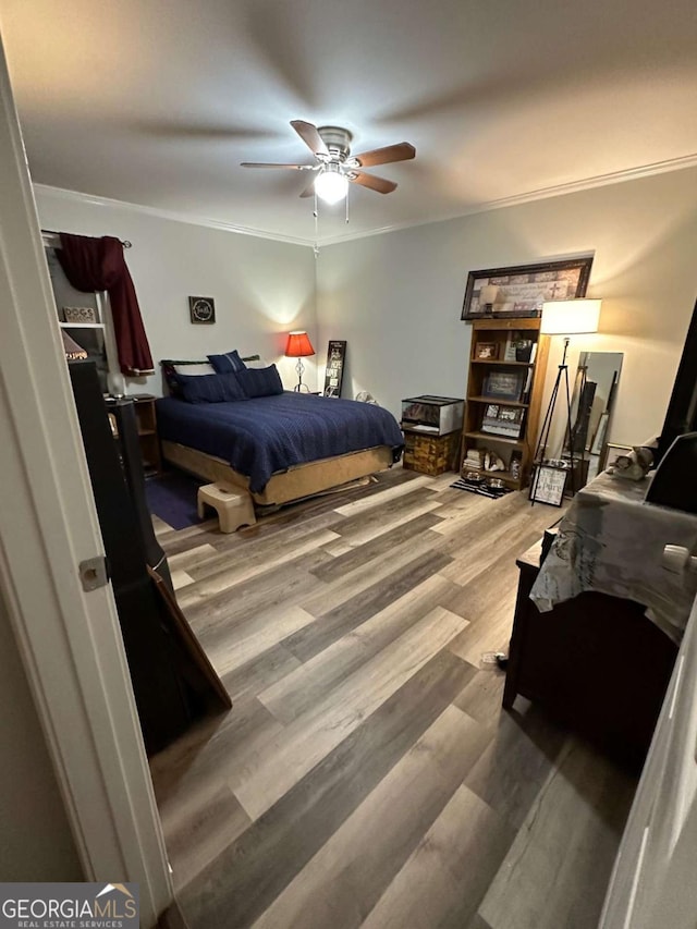 bedroom featuring crown molding, wood finished floors, and ceiling fan