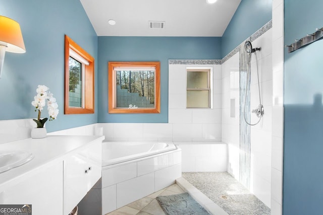 full bathroom featuring tile patterned floors, visible vents, a tile shower, and a garden tub