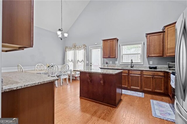 kitchen featuring light wood finished floors, brown cabinets, a sink, and a healthy amount of sunlight
