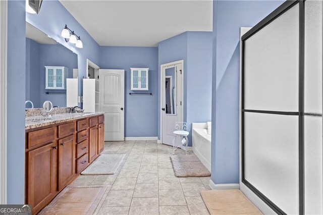 bathroom with baseboards, double vanity, tile patterned floors, a sink, and a garden tub