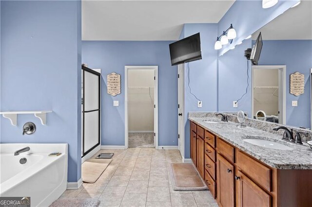 bathroom featuring double vanity, a sink, a walk in closet, and a bath