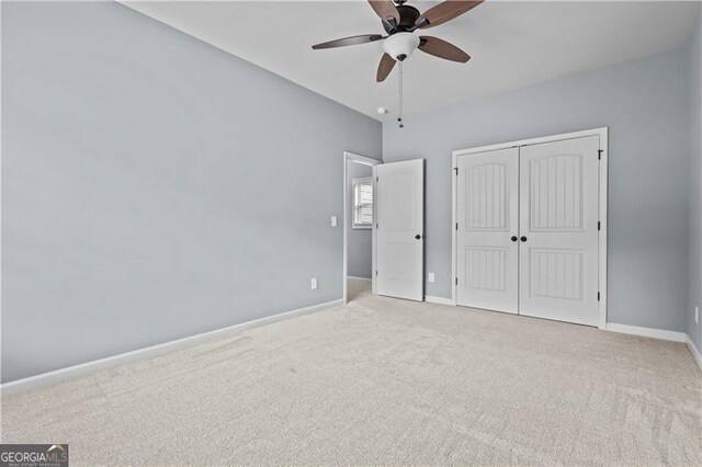 unfurnished bedroom with a closet, carpet, baseboards, and ceiling fan