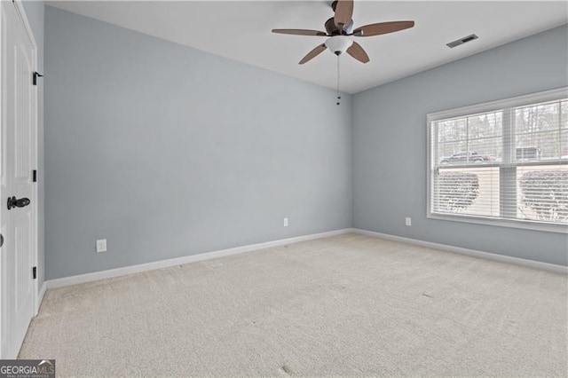 spare room featuring baseboards, visible vents, a ceiling fan, and light colored carpet
