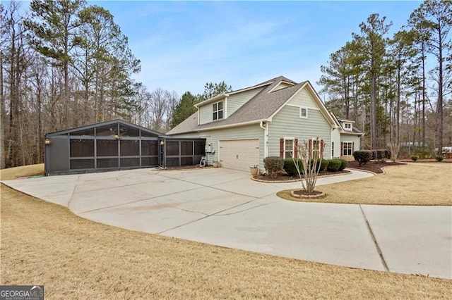 view of side of property featuring a sunroom, a garage, concrete driveway, and roof with shingles