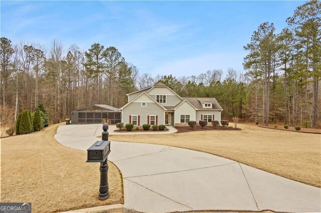 view of front of home with a front lawn, a view of trees, and curved driveway