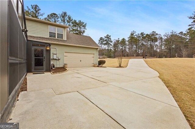view of home's exterior with concrete driveway, a garage, a yard, and a shingled roof