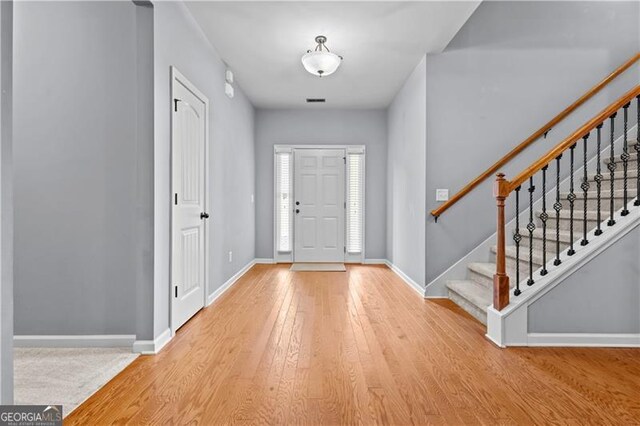 entryway featuring wood-type flooring, baseboards, and stairway