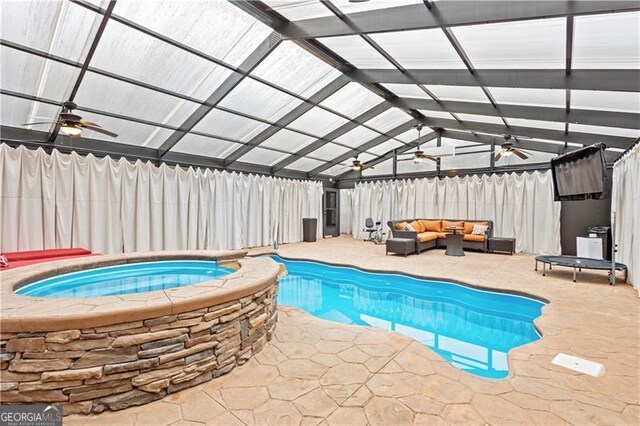 indoor pool featuring a fenced backyard, an outdoor living space, a ceiling fan, an in ground hot tub, and a patio area