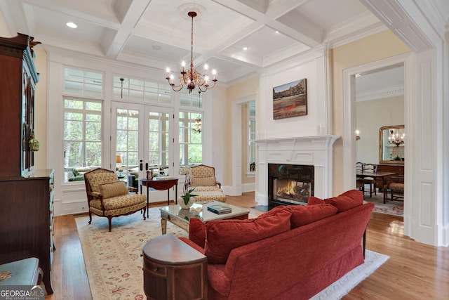 living room featuring a fireplace with flush hearth, light wood-style flooring, a chandelier, coffered ceiling, and beam ceiling