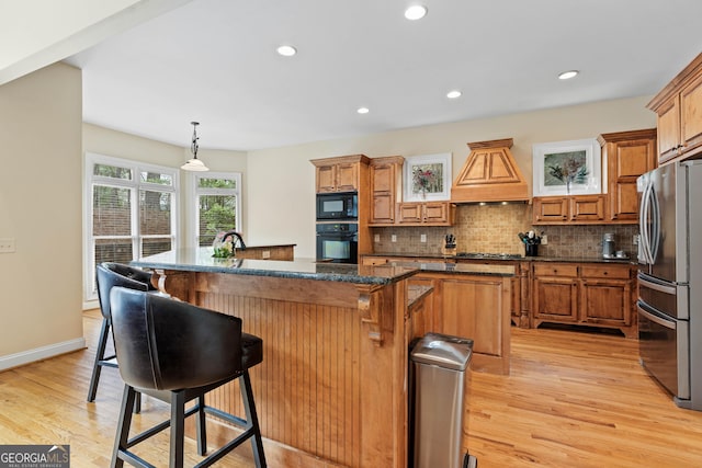 kitchen featuring a center island, backsplash, black appliances, and premium range hood