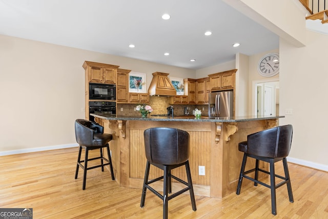 kitchen featuring light wood finished floors, baseboards, black appliances, and decorative backsplash