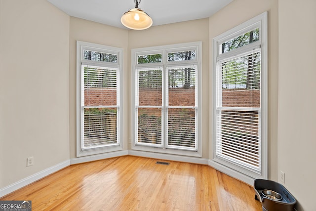 unfurnished dining area featuring a healthy amount of sunlight, visible vents, baseboards, and light wood-style flooring
