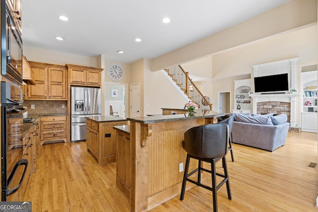 kitchen featuring light wood finished floors, a breakfast bar, black appliances, and a kitchen island