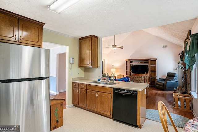 kitchen with dishwasher, a sink, freestanding refrigerator, a peninsula, and open floor plan