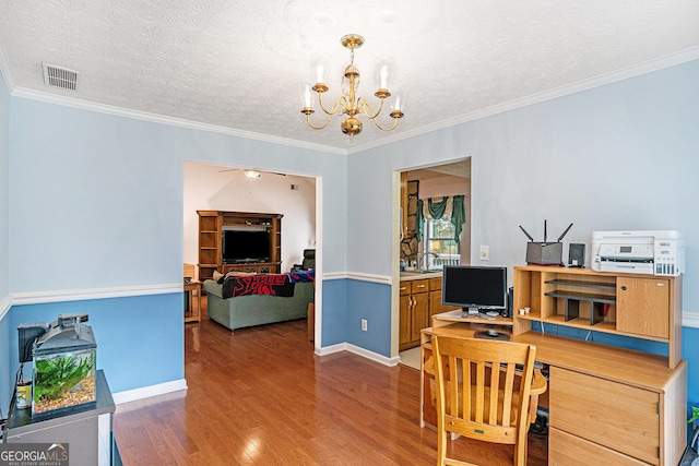 office space with visible vents, ornamental molding, wood finished floors, and ceiling fan with notable chandelier