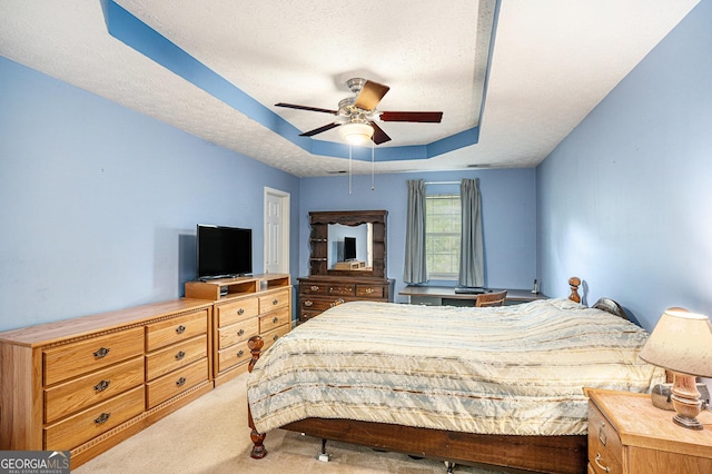 carpeted bedroom featuring a ceiling fan, a textured ceiling, and a raised ceiling