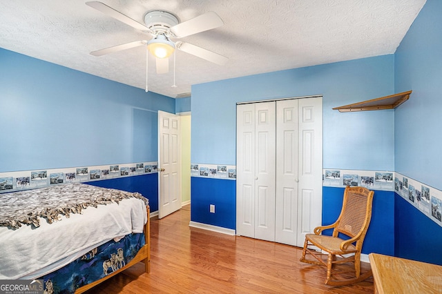 bedroom with a textured ceiling, ceiling fan, a closet, and wood finished floors