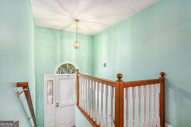 stairs with visible vents, a textured ceiling, and baseboards