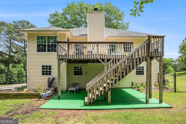 back of house featuring a shingled roof, fence, a wooden deck, and stairs