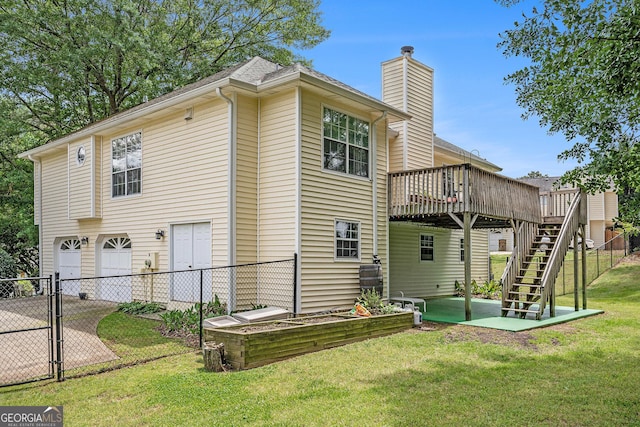 rear view of property featuring a wooden deck, a garage, stairway, fence, and a yard